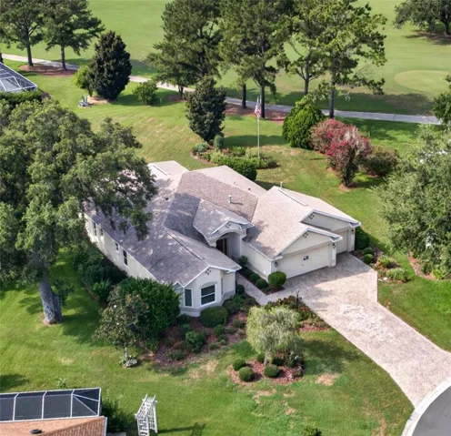 Elevated front view highlighting the home’s curb appeal, lush greenery, and desirable lot position surrounded by mature trees.