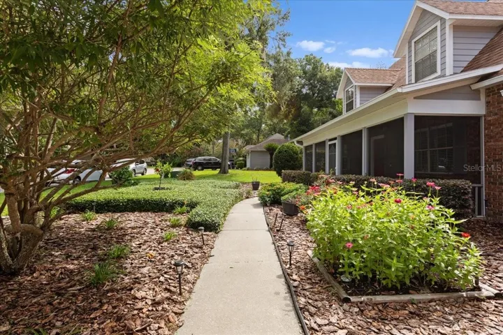 Sidewalk entry into home with beautiful landscaping.