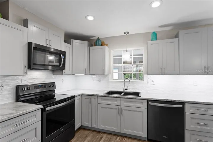 Updated shaker-style cabinetry and double-basin sink centered under window, and recessed lighting.