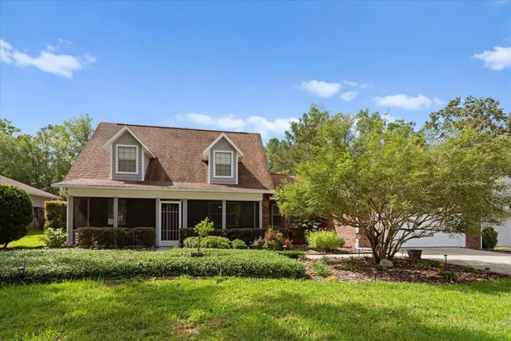 Charming Cape Cod-style home with classic dormer windows, a welcoming covered front porch, and beautifully landscaped yard.