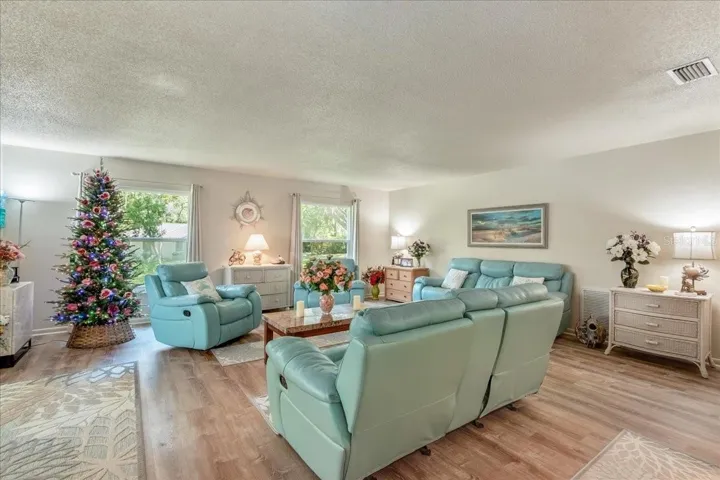 The heart of the home is warm, welcoming, and designed for gathering. This spacious living room features an open-concept layout, beautiful wood-look flooring, and abundant natural light, creating a comfortable setting for everyday living and entertaining.