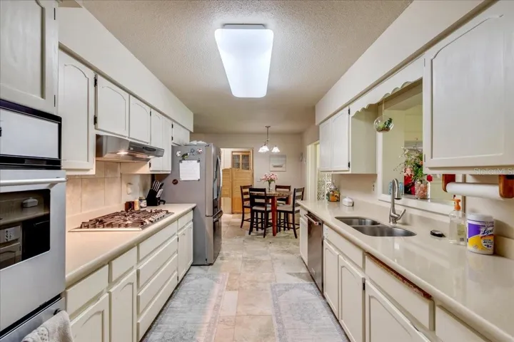 Full Kitchen ViewDesigned for both function and style, this well-appointed kitchen features quartz countertops, porcelain tile flooring, a propane gas cooktop, built-in double ovens, abundant cabinetry, and an adjoining breakfast nook—making meal preparation and entertaining effortless.