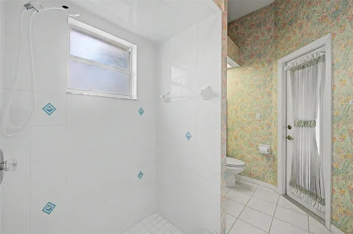 secondary full bathroom showcasing the spacious walk-in shower and convenient layout. A private exterior door provides direct access to the pool area, allowing this bathroom to function perfectly as a pool bath while also serving the secondary master bedroom.