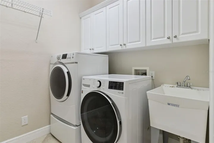 Inside laundry room off kitchen has cabinets, utility sink &amp; pantry