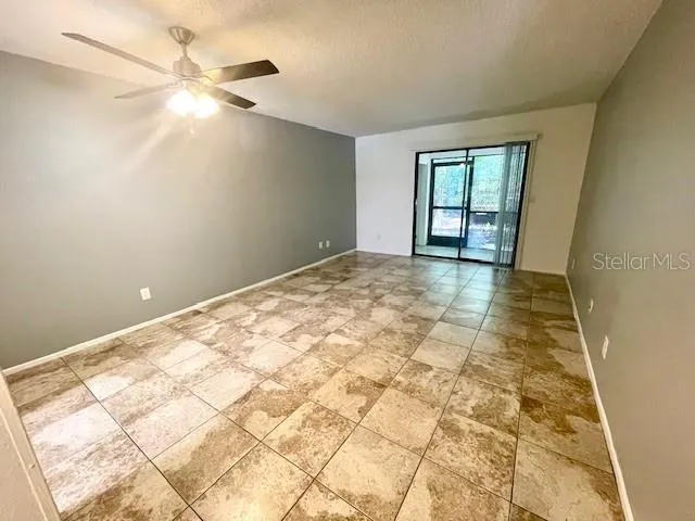 Spacious Great Room with tile flooring, ceiling fan, and sliding glass door out to a screen enclosed lanai.
