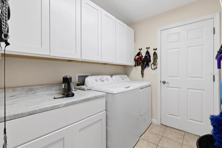 Inside laundry room with counter space and cabinets.  Through door to two car garage with screen over garage door.