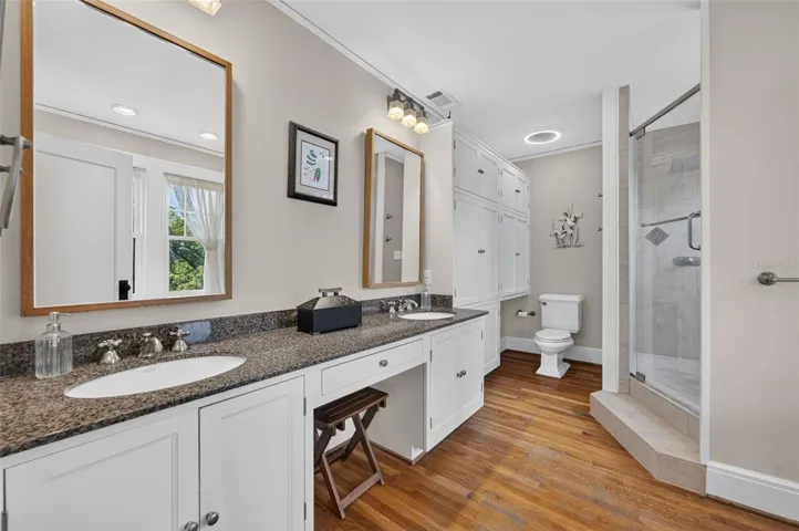 Primary bathroom with double vanity, walk-in shower, custom built-in storage and claw foot soaking tub