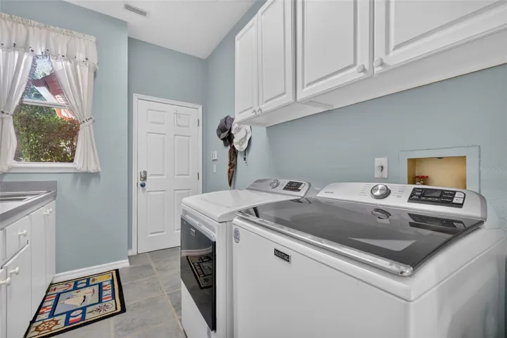 Laundry with cabinetry, sink, and washer and dryer that stay with the home