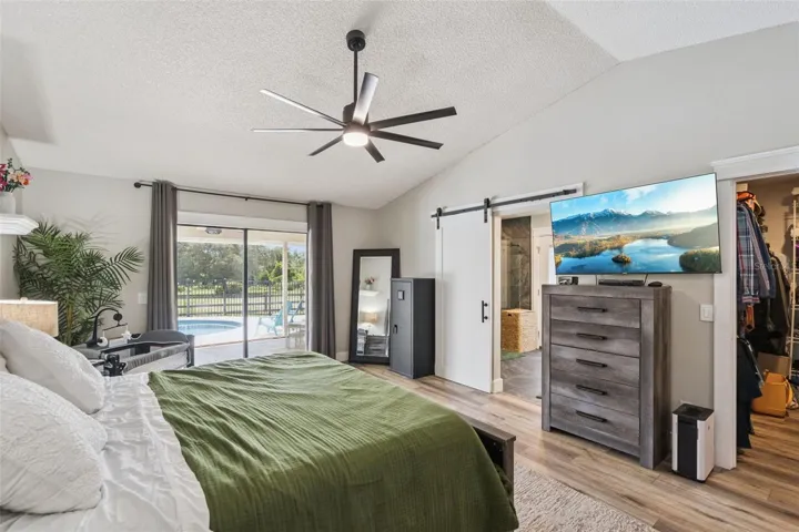 Primary bedroom with updated flooring, ceiling fan, lanai access, and natural light.
