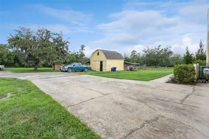 Driveway and side exterior view showing access to the home, barn, and acreage.