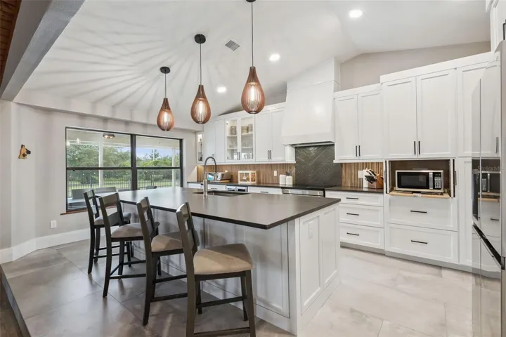 Bright dining and kitchen area with remodeled finishes, island seating, and backyard views.