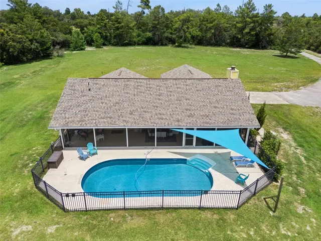 Aerial pool view showing the screened lanai, covered outdoor area, and surrounding yard.