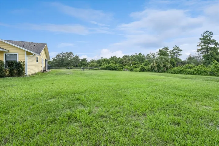 Side yard view to the west showing the home, open land, and usable outdoor space.