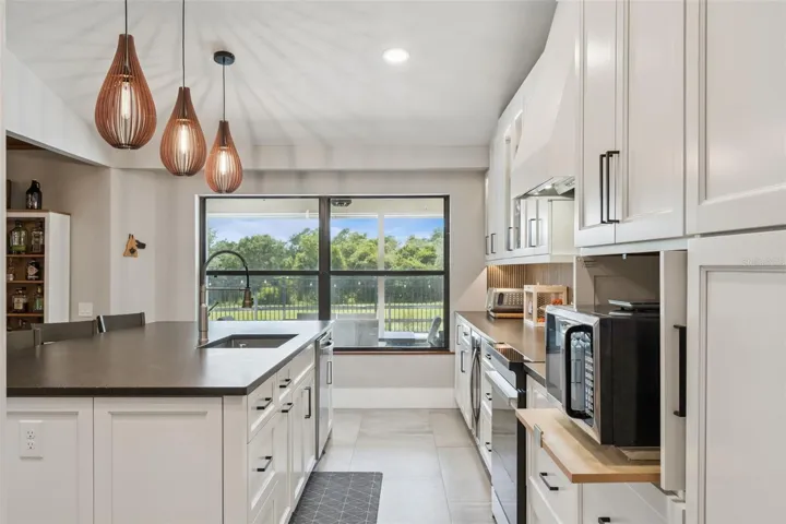 Kitchen sink area with updated cabinetry, backsplash, stainless appliances, and natural light.