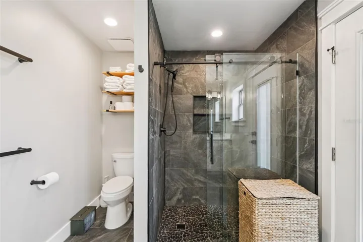 Renovated primary shower with glass enclosure, updated tile, and modern bathroom finishes.