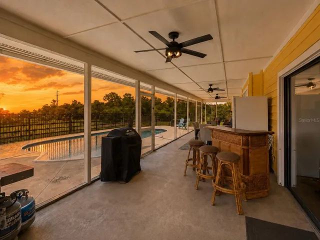 Covered screened lanai overlooking the pool and acreage, ideal for outdoor dining and Florida living.