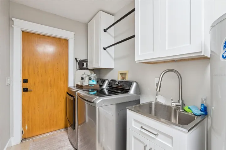 Utility and storage area with cabinetry, sink, and functional workspace.