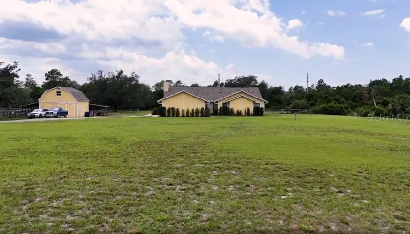 Front exterior view of the home with open yard, green space, and private acreage setting.