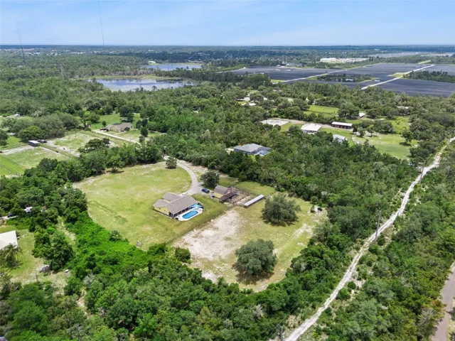 Elevated aerial view showing the home, barn, open acreage, and surrounding Central Florida landscape.