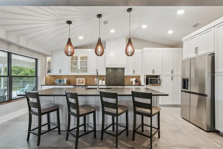 Newly Remodeled kitchen with leather-finished granite island, pendant lighting, white cabinetry, and seating.