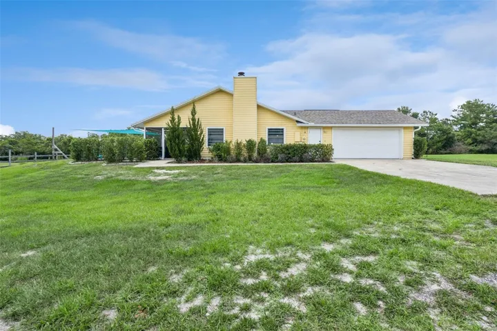 Side exterior view of the home with open yard, green space, and private acreage setting.