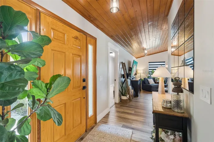 Entryway with double wood doors, warm wood ceiling detail, and view into the main living spaces.