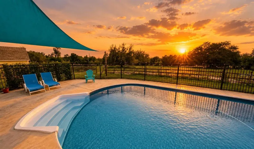 Private pool at sunset with shaded patio and peaceful views across the fenced acreage.