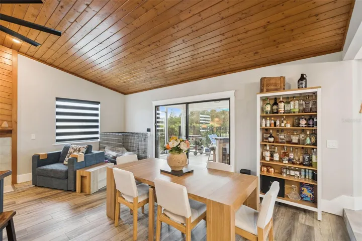 Main living area with wood ceiling detail, built-in shelving, and access toward the dining and kitchen spaces.
