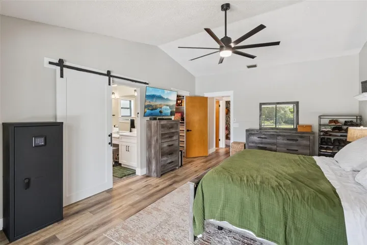 Primary bedroom with barn door detail, access to renovated bathroom, and flexible furniture layout.