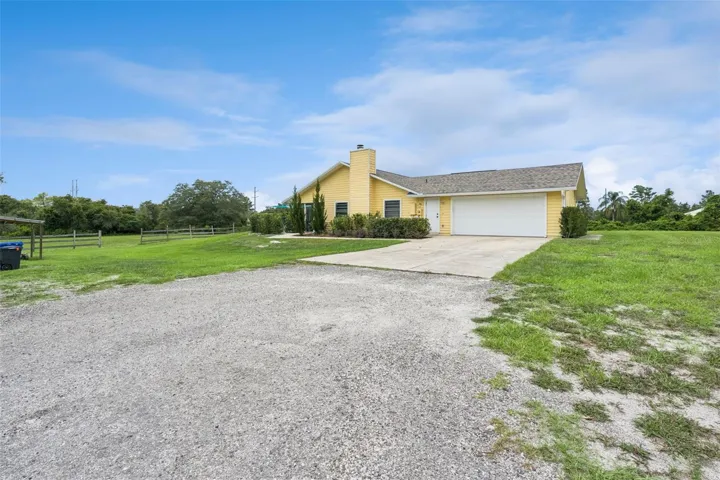 Long gated driveway approach highlighting the private acreage setting and spacious front exterior.
