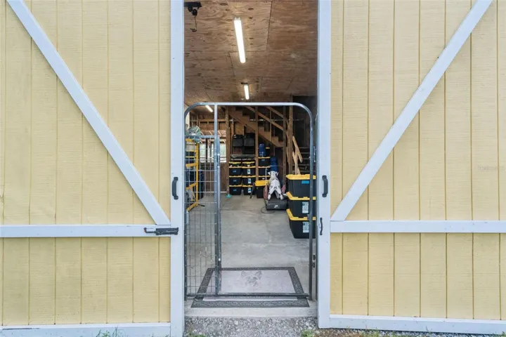 Barn entry with wide double doors and access to workshop, storage, and animal-use areas.