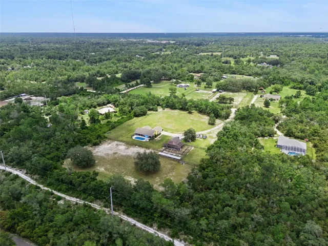 Wide aerial view highlighting the private acreage setting and nearby trail corridor.
