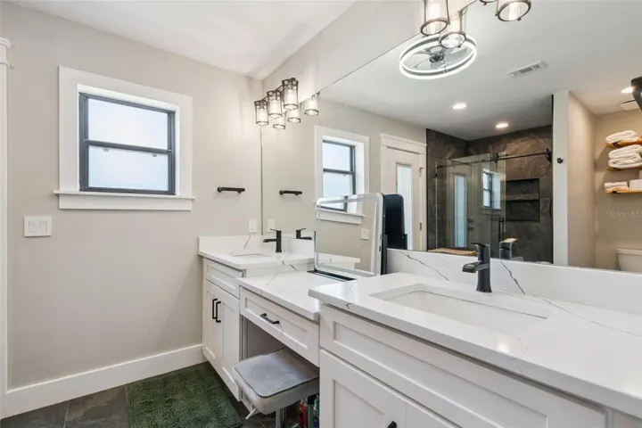 Fully renovated primary bathroom with dual vanities, updated flooring, modern lighting, and bright finishes.