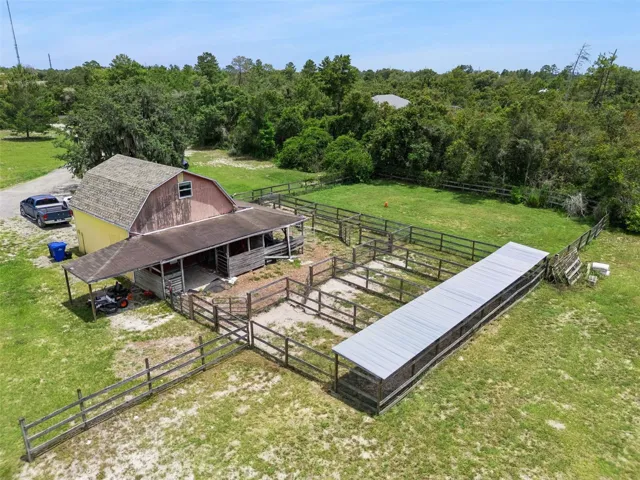 Aerial view of barn, fenced areas, pool area, and usable acreage behind the home.