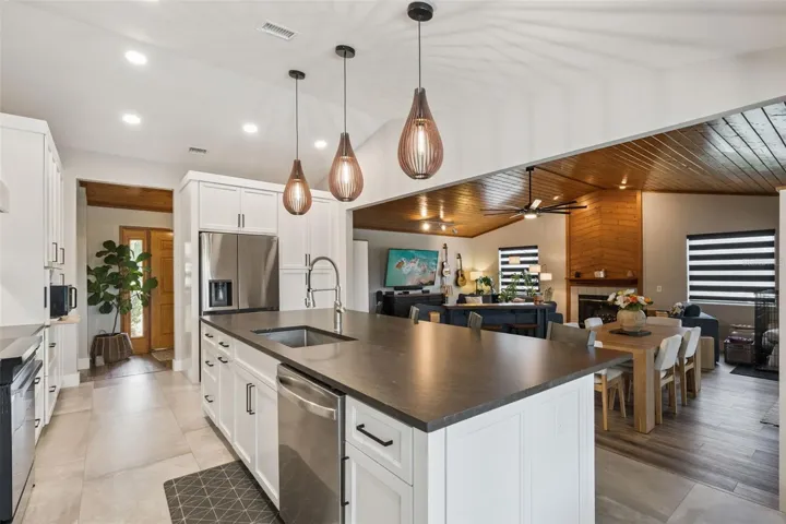 Kitchen view showing the large island, updated cabinetry, backsplash, and open connection to the living area.
