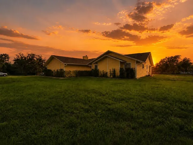 Front exterior view of the home with open yard, green space, and private acreage setting.