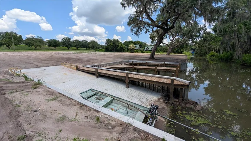 Boat ramp and double boat dock looking out on cleared property and canal