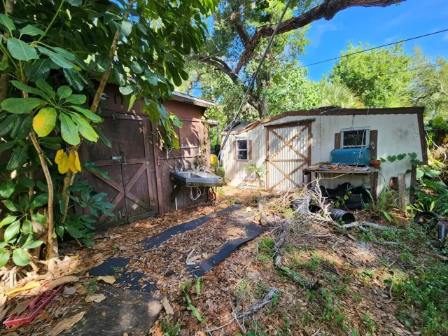 brown wooden doors left of sink provide access to workshop area attached to back of structure.  Large storage shed to the right