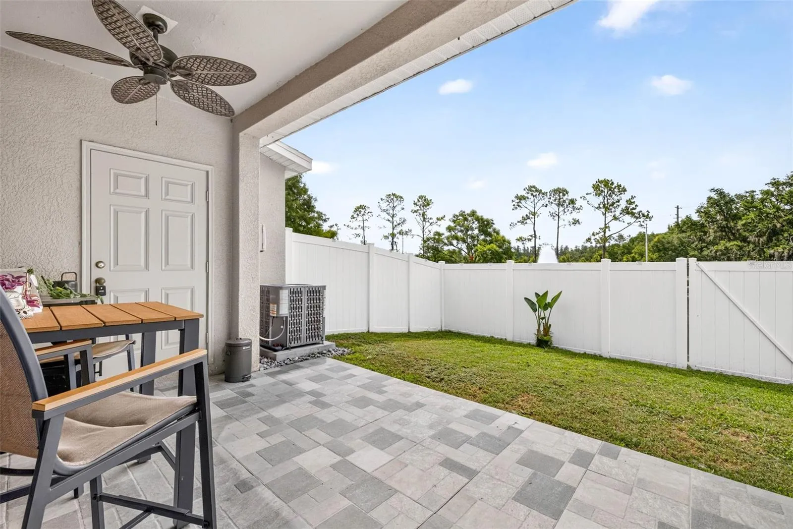 Outdoor living space with upgraded pavers and fenced yard.