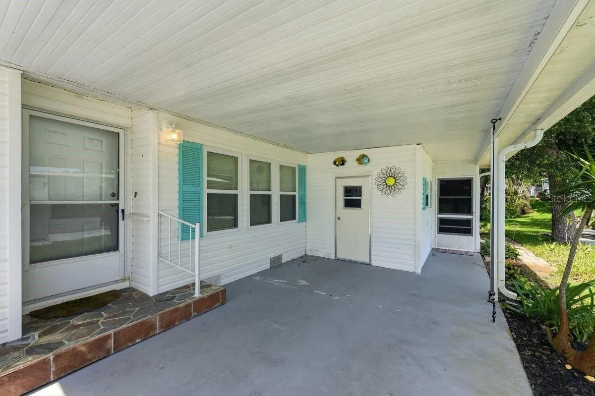 On Carport showing Front door to the left, Carport Storage in Rear; and Florida Room on Right. Notice the great Hurricane tie downs on the carport. Gutters.
