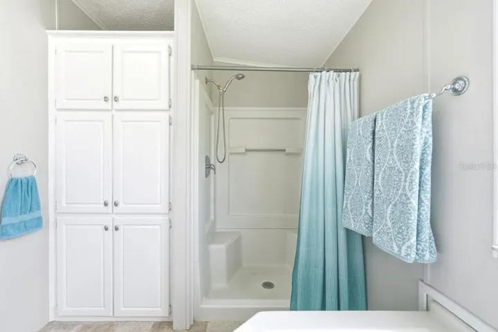 View from Tub showing Shower with seating and Linen closet