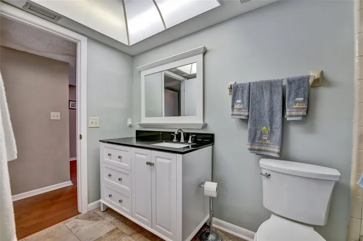 Newer vanity, mirror, and toilet in guest bathroom
