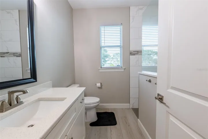 Alternate view of the beautifully appointed guest bath highlights the seamless transition to the walk-in shower. The neutral color palette and high-end materials carry through, matching the luxury standard found across the entire residence.