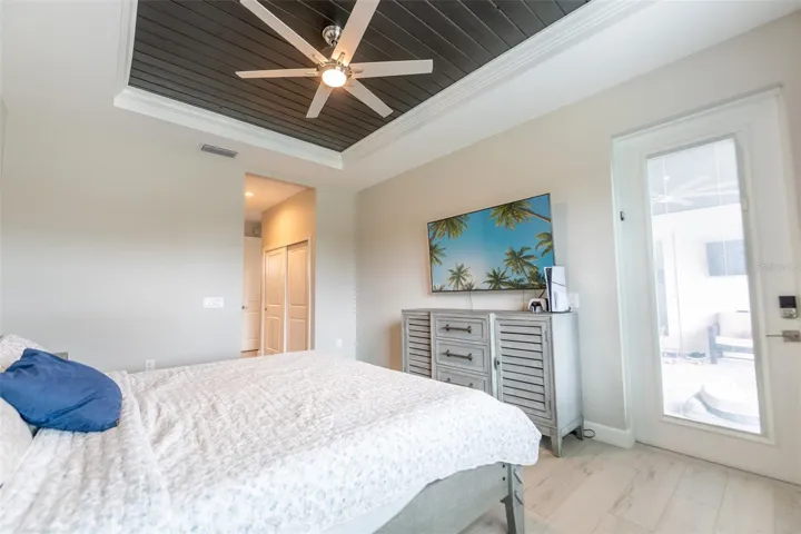 Exceptional master retreat detail showing the private glass exterior door that opens directly onto the outdoor pool patio area. Enjoy early morning coffee or late-night swims with effortless, seamless access directly from your bedroom.