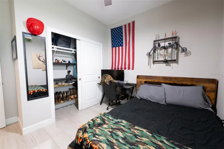 Another perspective of the secondary bedroom showcases the excellent storage layout. The room comes equipped with a large closet featuring custom built-in organization, shelving, and sliding doors, making it an ideal setup for kids, guests, or a dedicated home office.