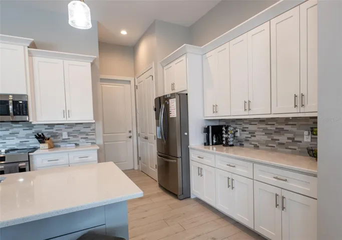 Detail view of the gourmet kitchen highlighting the extensive counter space, premium mosaic tile backsplash, and an abundance of custom white shaker cabinetry. Perfect for meal prep and storage, this kitchen blends high-end functionality with modern style.