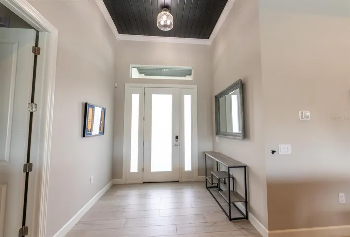 Make a grand entrance! The bright foyer welcomes you with high ceilings, a dramatic dark wood ceiling accent, custom lighting, modern wood-look tile flooring, and a premium front door with glass sidelights that flood the home with natural light.