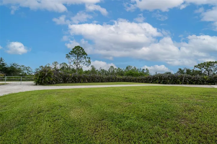 Welcome to your private, fully cleared country oasis! This stunning wide view highlights the expansive, beautifully manicured green lawn framed by established tropical privacy hedges. There is endless space on this acreage lot to customize your perfect outdoor homestead setup.