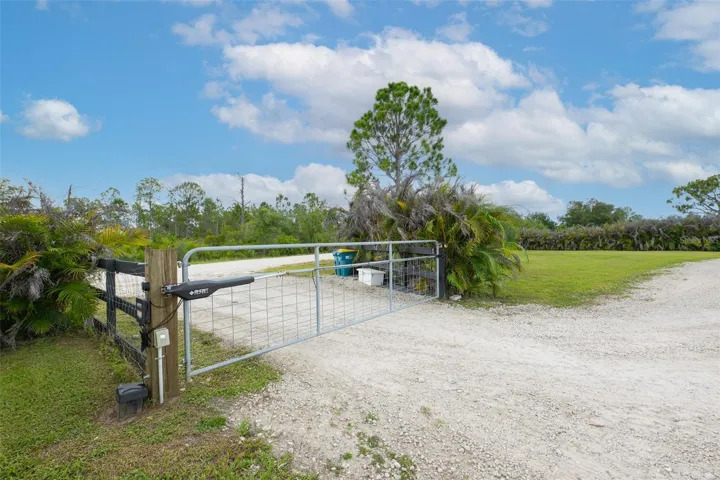 Security and convenience blend seamlessly at the property entrance. A long, private gravel driveway is secured by a heavy-duty ranch-style fence and an automatic farm gate, offering ultimate peace of mind and controlled access to your custom estate.