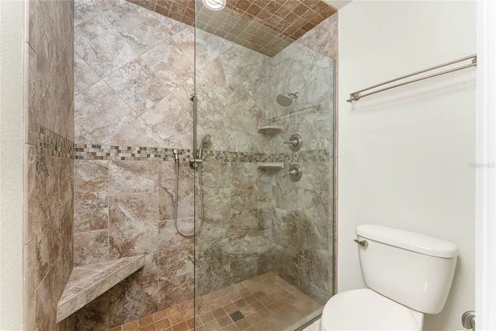 Floor to ceiling porcelain tile shower with custom built in ninch and corner shelves